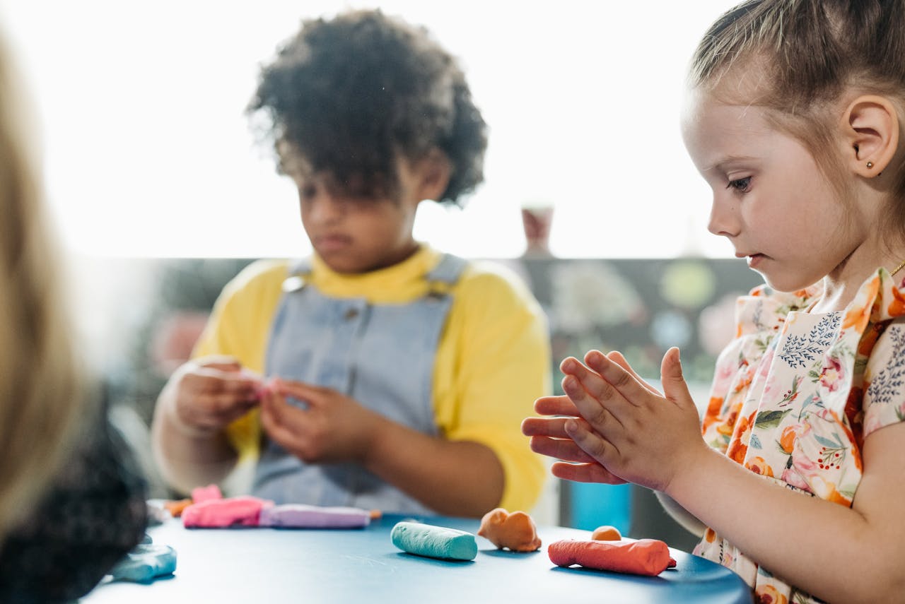 Young children playing with colorful clay indoors, enhancing creativity and learning.